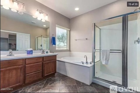 A modern bathroom with a large mirror, double sinks, and a glass shower door.