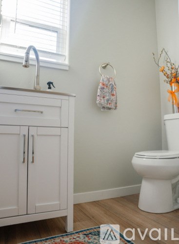 A white toilet sits in a bathroom next to a sink and a cabinet.