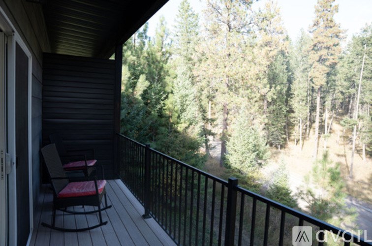A balcony with a rocking chair and a view of trees.