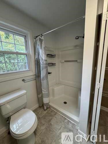 A white toilet sits next to a bathtub in a bathroom.