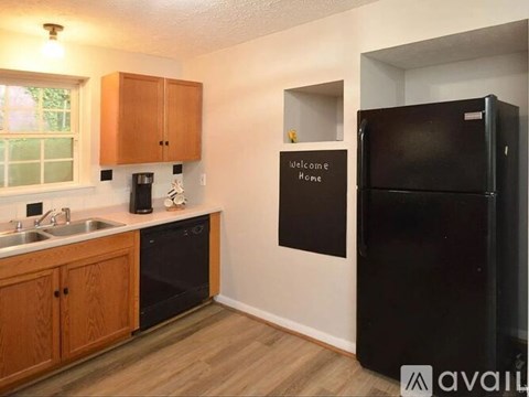 A kitchen with wooden cabinets and a black fridge.