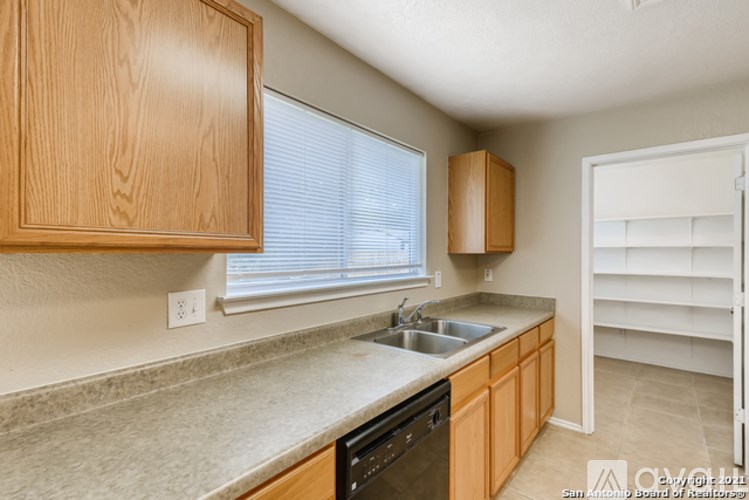A kitchen with wooden cabinets and a black dishwasher.