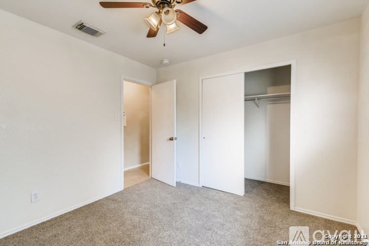A room with a ceiling fan and carpeted floor.