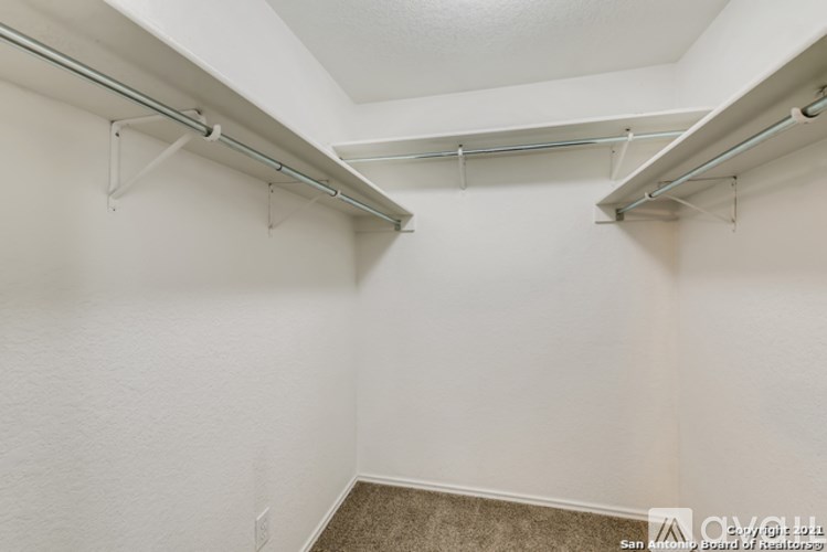 A white wall with a metal rod and hooks.