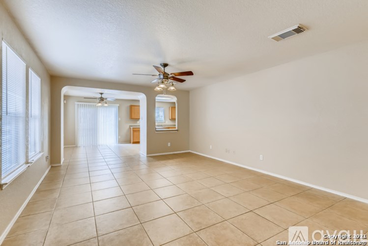 A spacious room with a ceiling fan and tiled flooring.