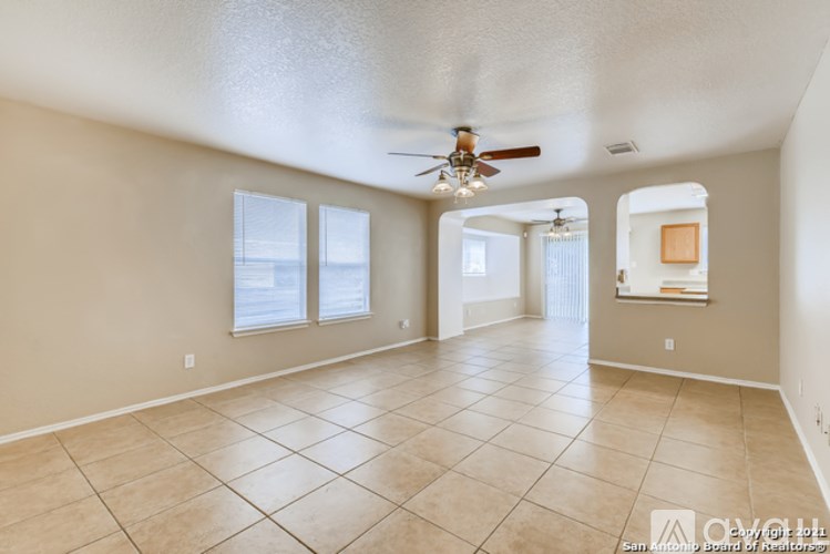 A spacious room with a ceiling fan and tile flooring.