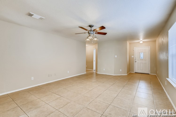 A spacious room with a ceiling fan and tiled floor.