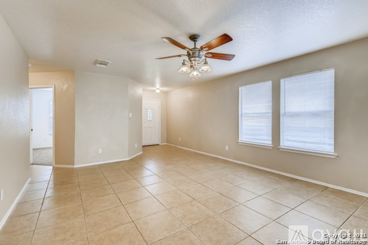 A spacious room with a ceiling fan and tiled flooring.