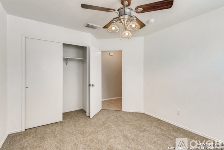A room with a ceiling fan and carpeted floor.