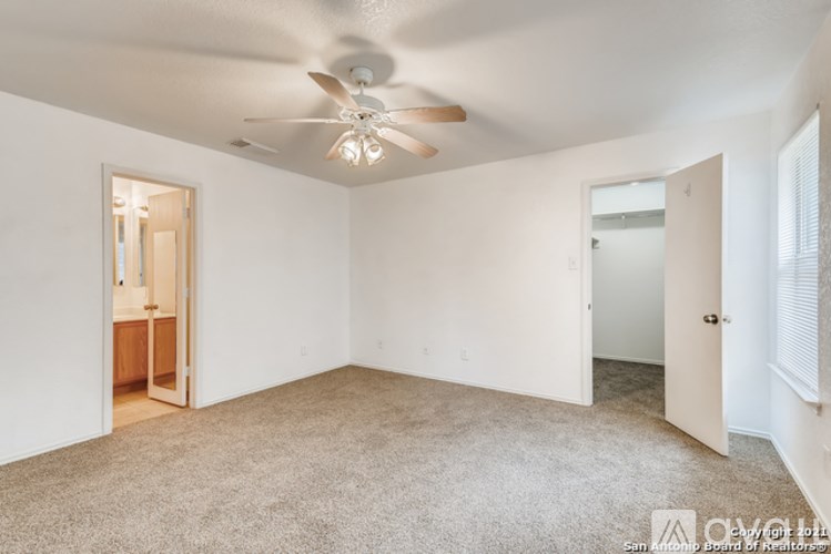 A spacious room with a ceiling fan and carpeted floor.