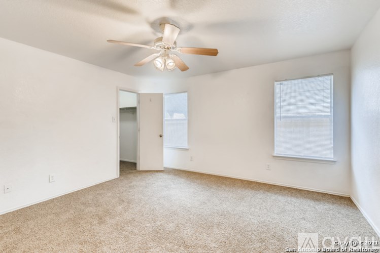 A spacious room with a ceiling fan and carpeted floor.