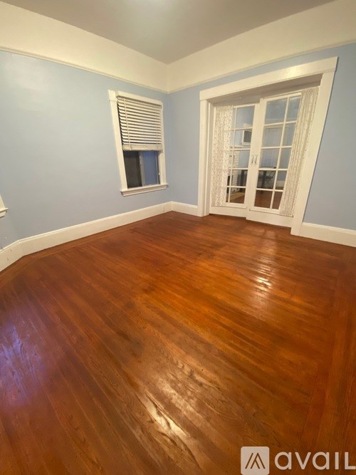A room with wooden flooring and a window with blinds.