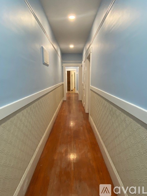 A long hallway with wood floors and white walls.