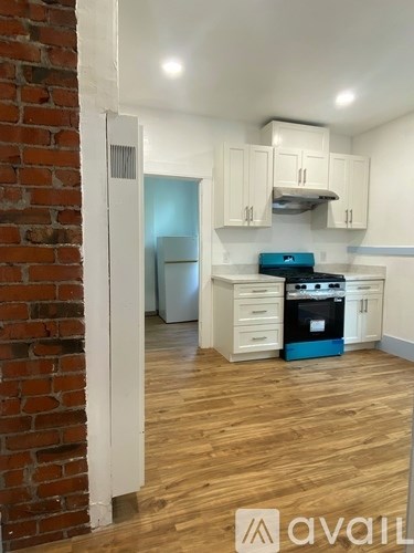 A kitchen with a brick wall and wooden floors.