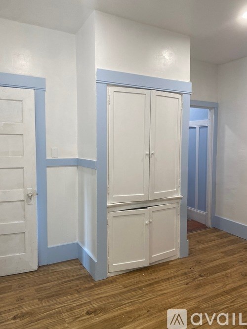 A room with white and blue walls and wooden floors.