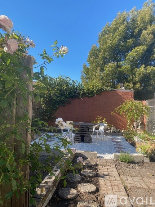 A garden with a wooden fence, a table and chairs, and a pool.