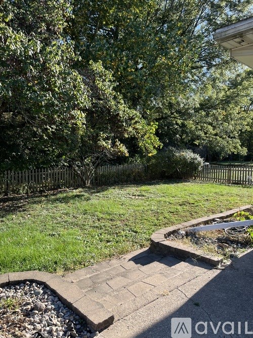 A backyard with a brick pathway and a small garden bed.