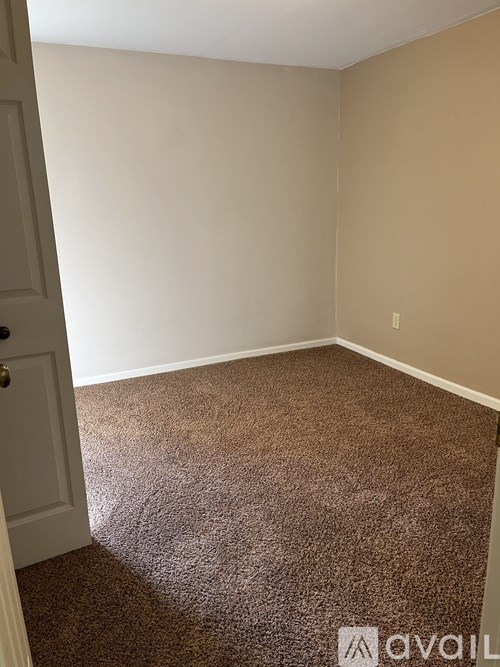 A room with brown carpet and a white door.