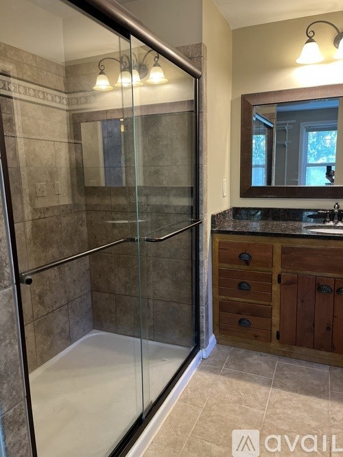 A bathroom with a glass shower stall and a wooden vanity.