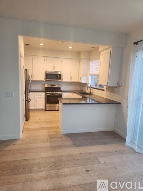A kitchen with white cabinets and a black countertop.