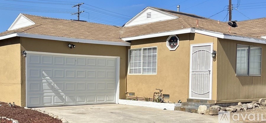 A tan house with a white garage door and a white door with a window above it.