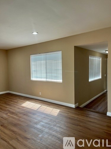 A room with wooden flooring and a window with blinds.