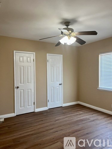 A room with a ceiling fan and two doors.