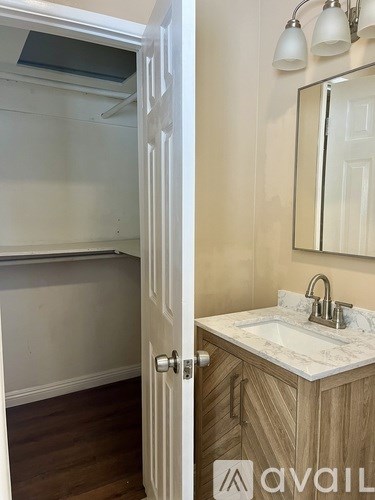 A bathroom with a sink, mirror, and wooden cabinet.