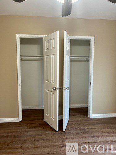 Two white doors in a room with wooden floors.