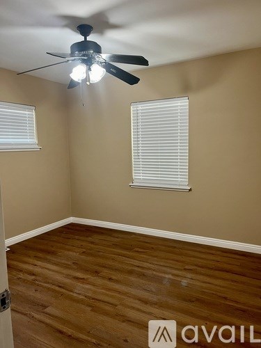 A room with a ceiling fan and a window with blinds.