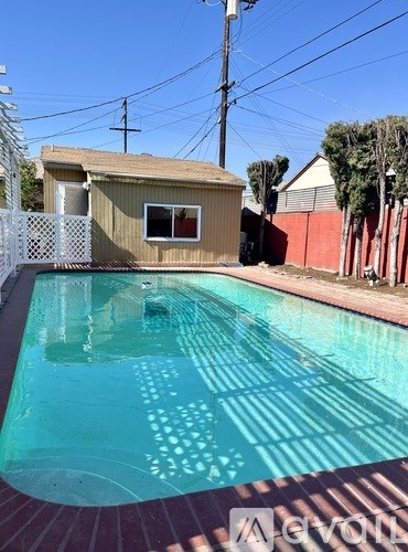 A pool in a backyard with a house and a fence.