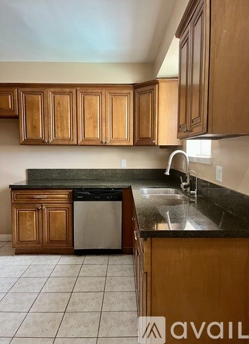 A kitchen with wooden cabinets and a black dishwasher.