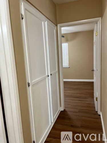 A hallway with white doors and wooden floors.