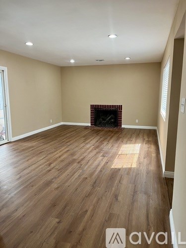 A living room with a fireplace and wooden floors.
