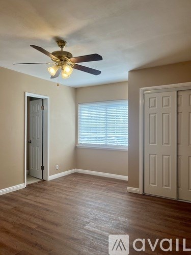 A room with a ceiling fan and two doors.