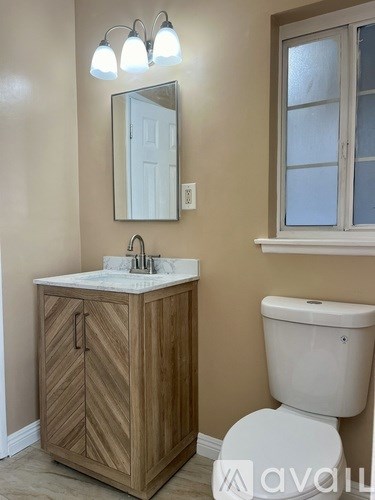 A bathroom with a wooden vanity and a white toilet.