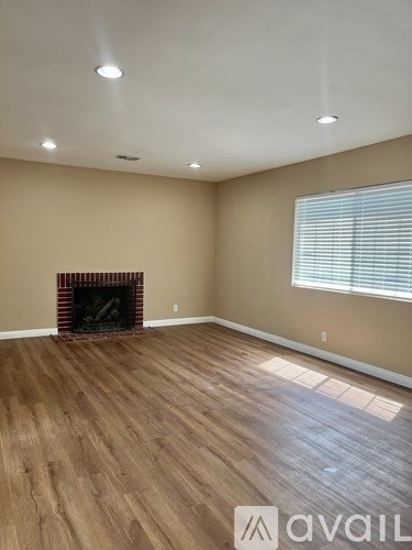 A room with a fireplace and wooden flooring.