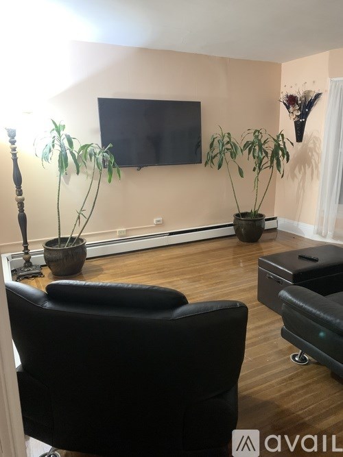 A living room with a black leather chair and a flat screen TV mounted on the wall.