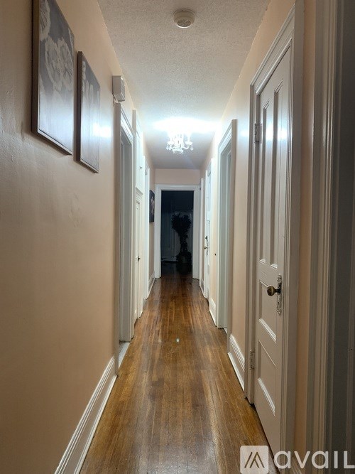 A long hallway with wood floors and white walls.