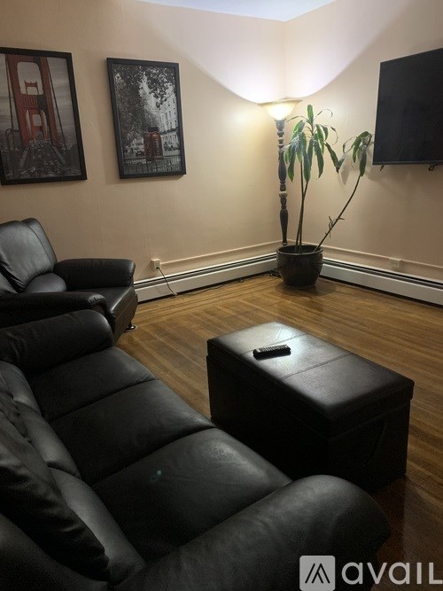 A living room with a black leather couch and ottoman.