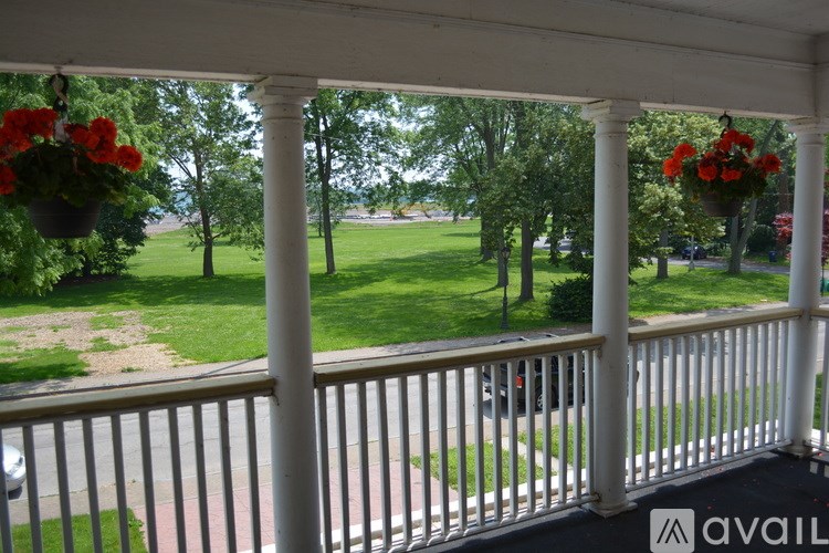 A porch with a view of a green lawn and trees.