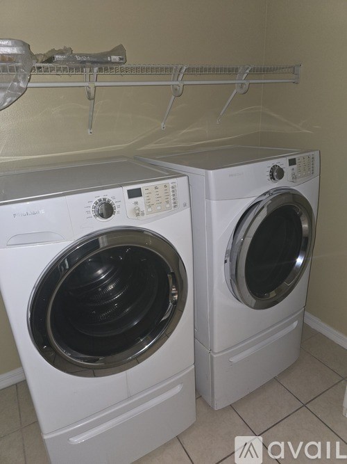 Two white front loading washing machines in a laundry room.