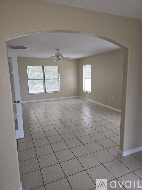 A spacious room with a fan and tiled flooring.