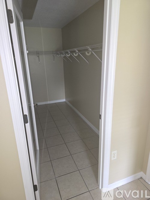 A walk in closet with a white door and a white interior.