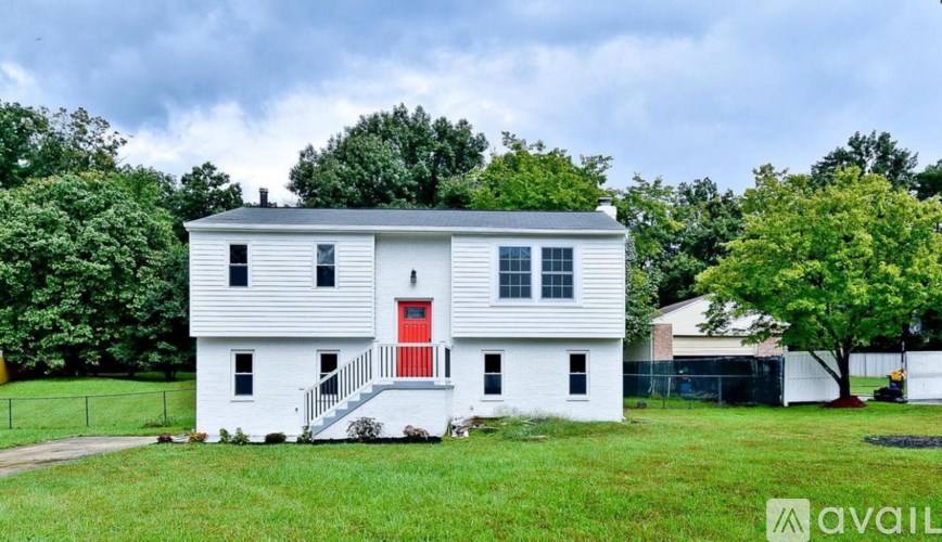A white house with a red door is for sale.