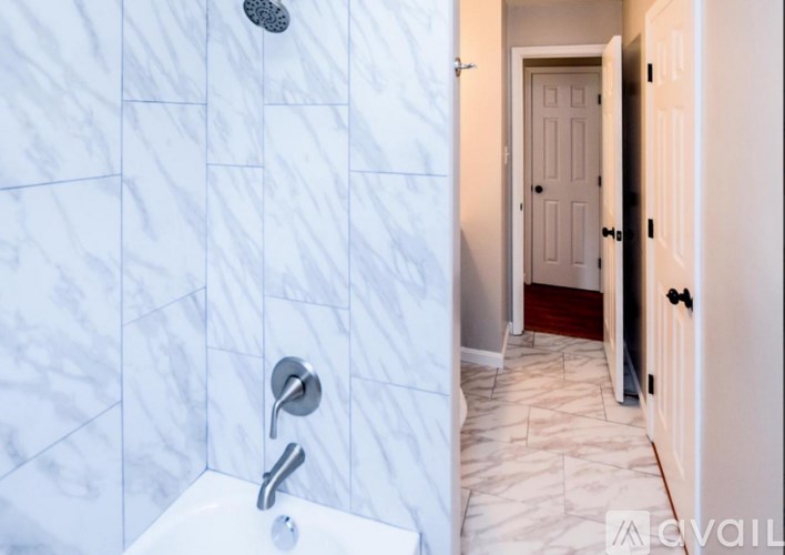 A white bathroom with a marble tile shower.
