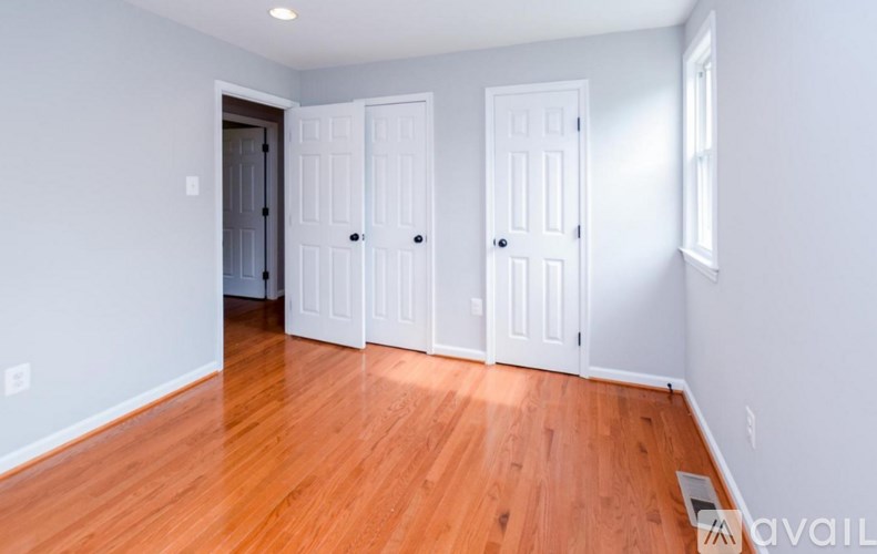 A room with wooden floors and white walls, featuring a door with a window on the side.
