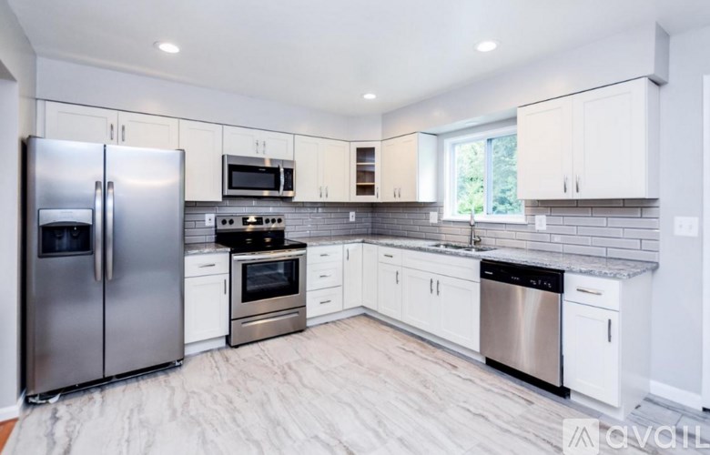 A modern kitchen with white cabinets and stainless steel appliances.