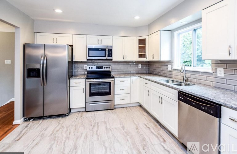 A modern kitchen with stainless steel appliances and wooden flooring.