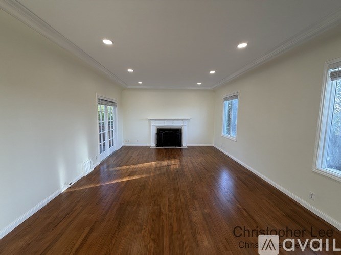 A spacious room with wood flooring and a fireplace.